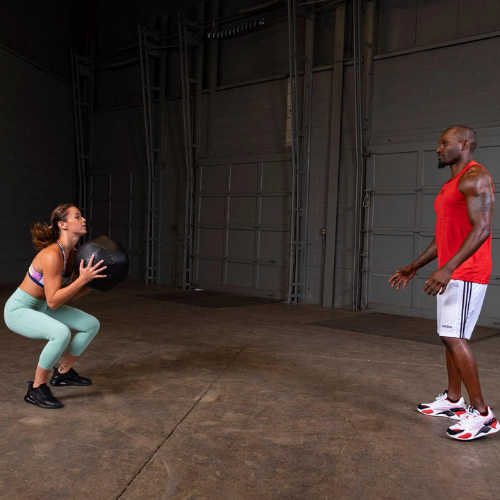 A man and woman training with the Body-Solid Dynamax Wall Ball BSTDYN