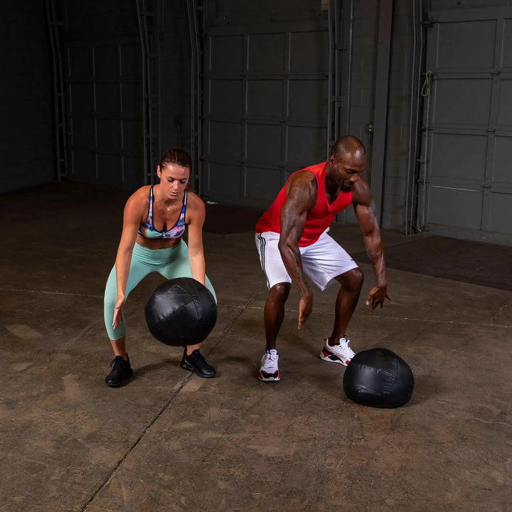 A man and woman training with the Body-Solid Dynamax Wall Ball BSTDYN