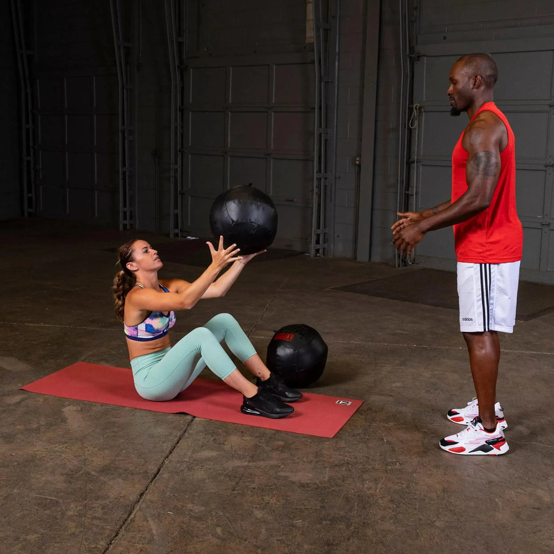 A man and woman training with the Body-Solid Dynamax Wall Ball BSTDYN