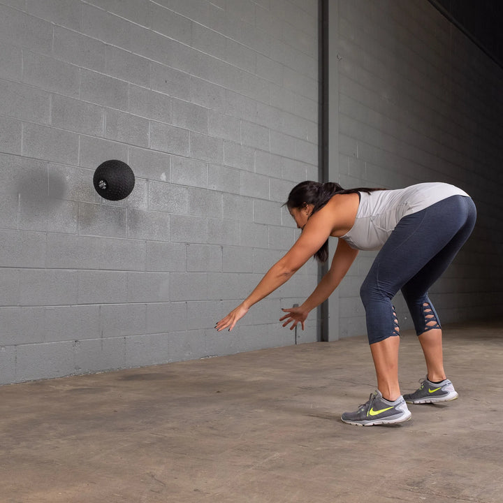 A woman training with a Body-Solid Tire Tread Slam Ball BSTTT