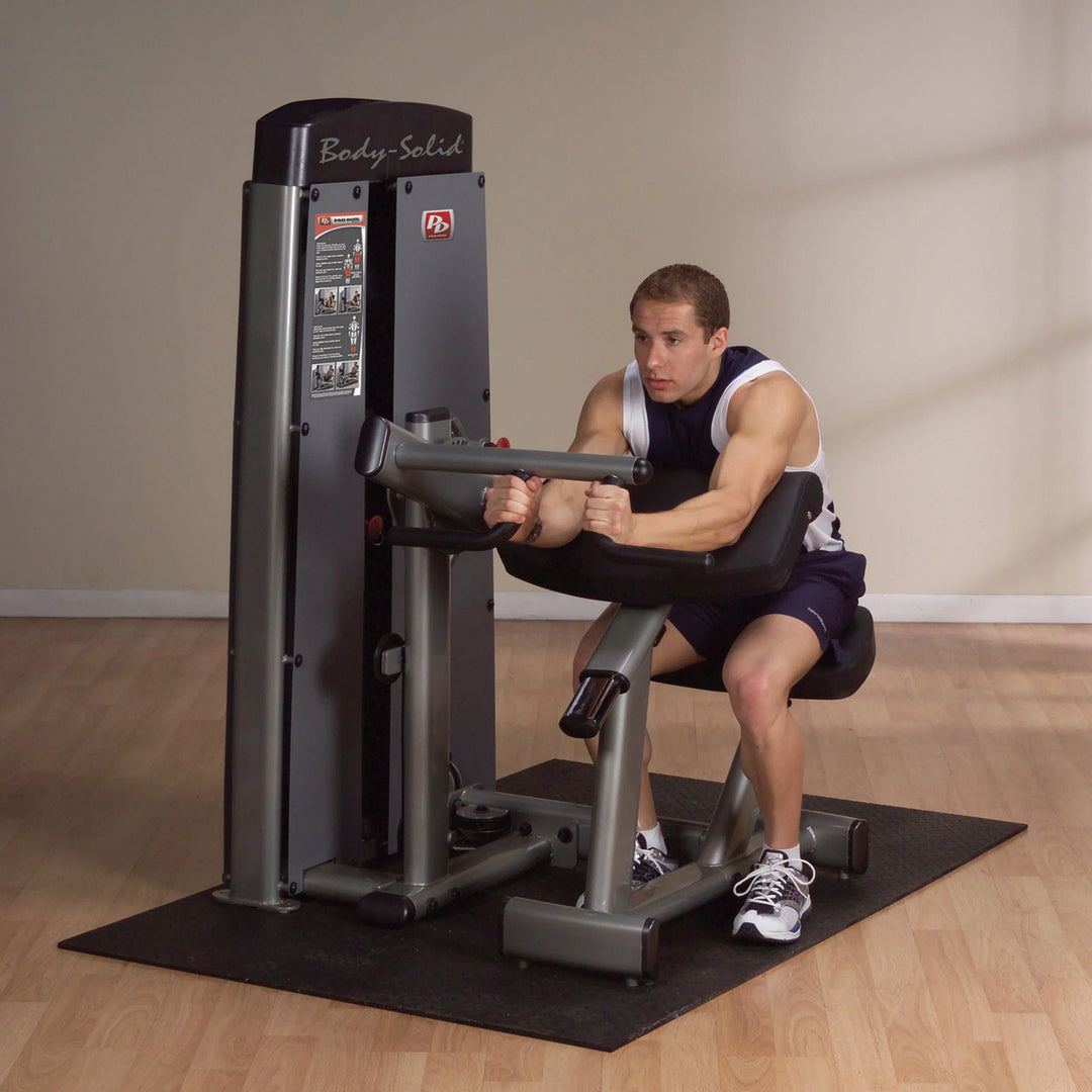 A man training on the Body-Solid Bicep and Tricep Machine DBTCSF
