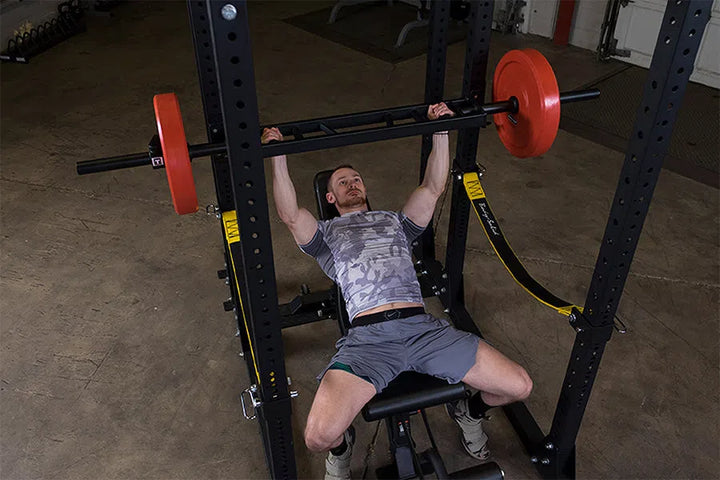 A man training with the Body-Solid Multi Grip Bench Press Bar OMG86