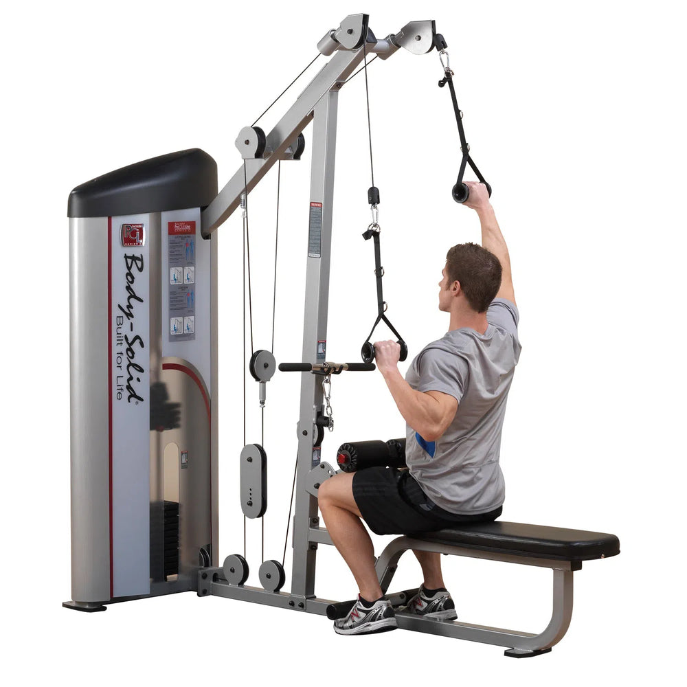 A person is strength training on a Body-Solid Pro Clubline Lat Pulldown and Row Machine (S2LAT) at the gym, using the wide-grip bar single-handedly while seated, dressed in athletic wear. The machine incorporates weights, pulleys, and cables.