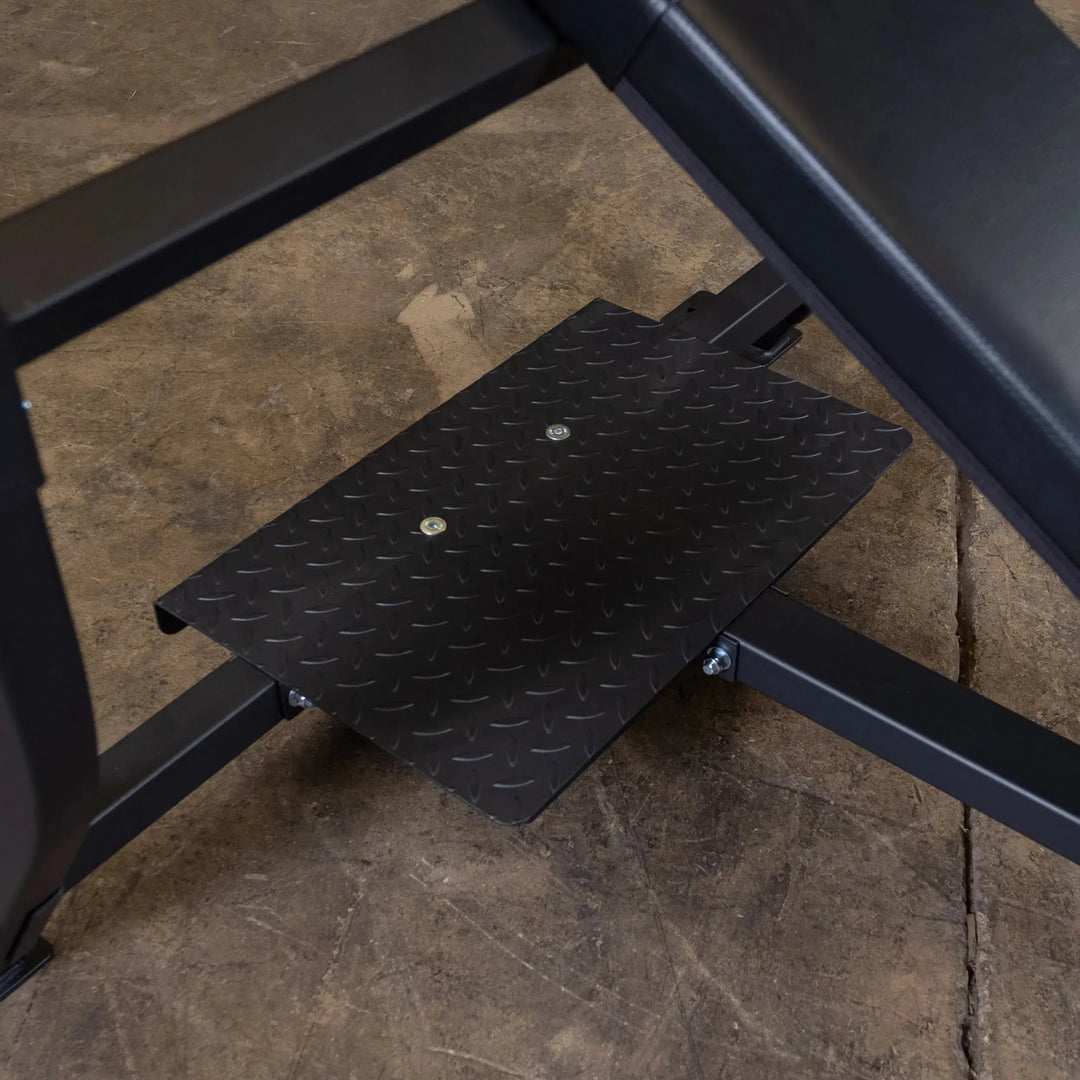 Close-up of a black metal platform with diamond-pattern texture in a gym, part of the Body-Solid Pro Clubline Olympic Incline Bench (SOIB250) on concrete. Ideal for upper body workouts with commercial fitness equipment efficiency.