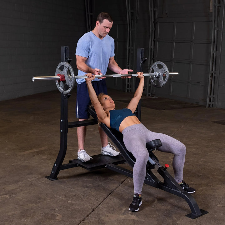 A woman training with a coach on the Body-Solid Commercial Olympic Incline Bench SOIB250