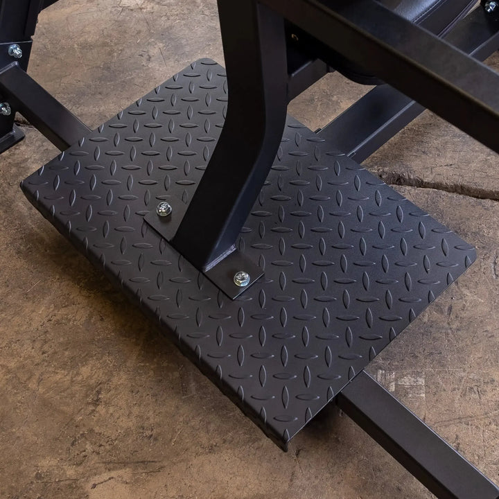 Zoomed in on the Body-Solid Pro Clubline Olympic Shoulder Press Bench (SOSB250) featuring a robust steel base with an angled support arm, diamond-patterned platform, visible bolts, and a matte, industrial finish. Ideal for gym setups with its durable design.