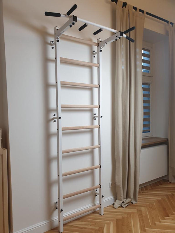 The BenchK Home Swedish Ladder w/ Pull-Up Bar (721) by BenchK, featuring white and wooden elements, is installed beside a window with beige curtains on a patterned wooden floor, adding an elegant home gym feel.