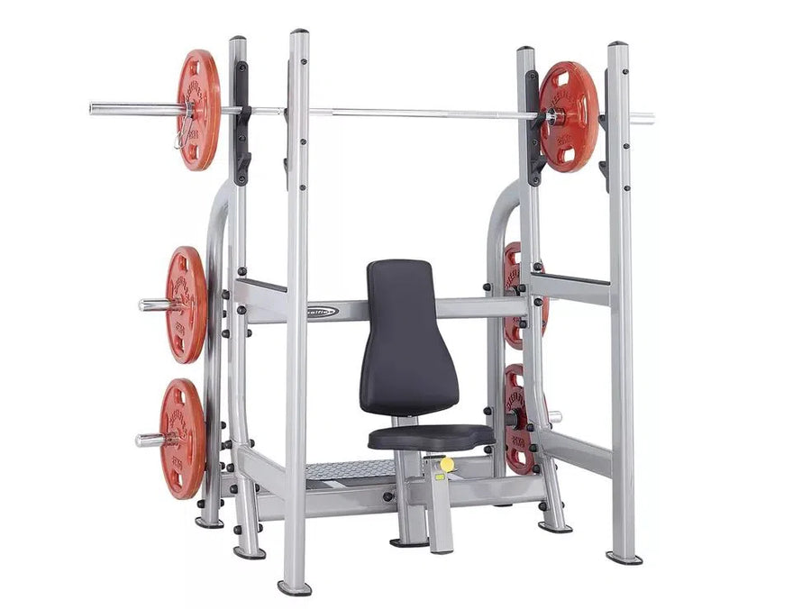 The Steelflex Olympic Military Press Bench (NOMB) is ideal for shoulder strength training, featuring a silver frame, red plates, and a padded black seat. Multiple barbell holders offer versatility in exercises.