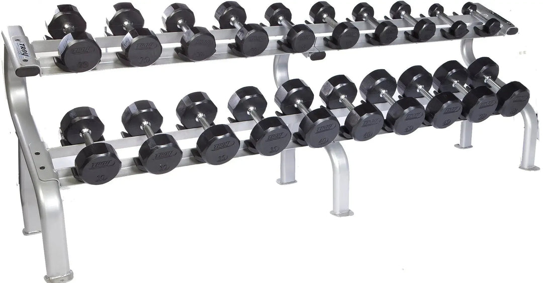 The TROY Barbell 5-50 lb Rubber Commercial Dumbbell Set showcases pairs of black hex dumbbells neatly organized on a sturdy two-tiered metal rack, featuring a silver frame with safety features for secure placement during workouts.