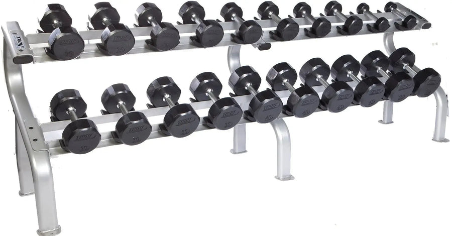The TROY Barbell 5-50 lb Rubber Commercial Dumbbell Set showcases pairs of black hex dumbbells neatly organized on a sturdy two-tiered metal rack, featuring a silver frame with safety features for secure placement during workouts.