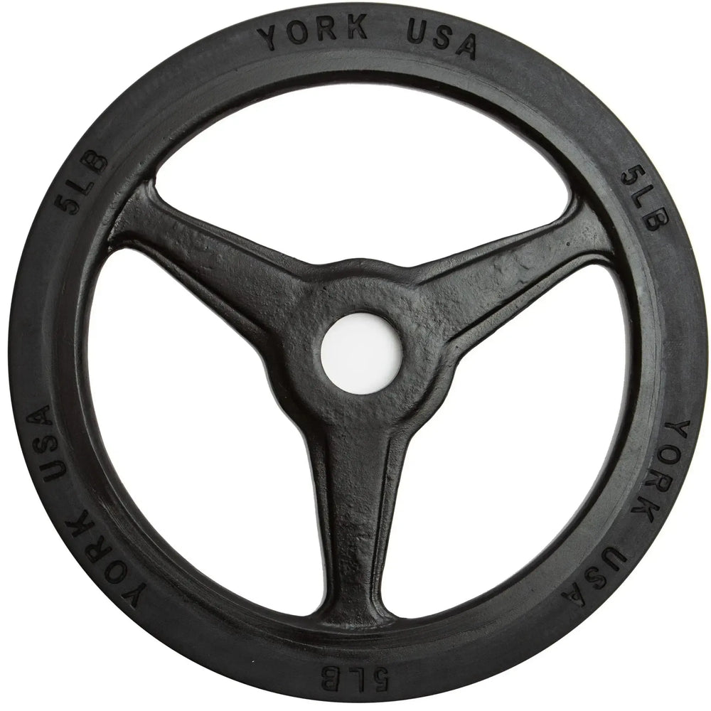 A York Barbell Bumper Grip Plate features a black, three-spoked design with York USA and 5 LB around the edge. Its rimmed with rubber for durability and has a central hole for barbell loading, ideal for commercial collections.