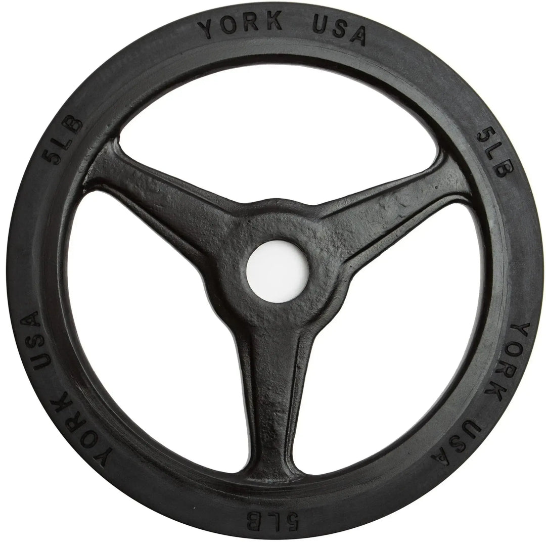A York Barbell Bumper Grip Plate features a black, three-spoked design with York USA and 5 LB around the edge. Its rimmed with rubber for durability and has a central hole for barbell loading, ideal for commercial collections.