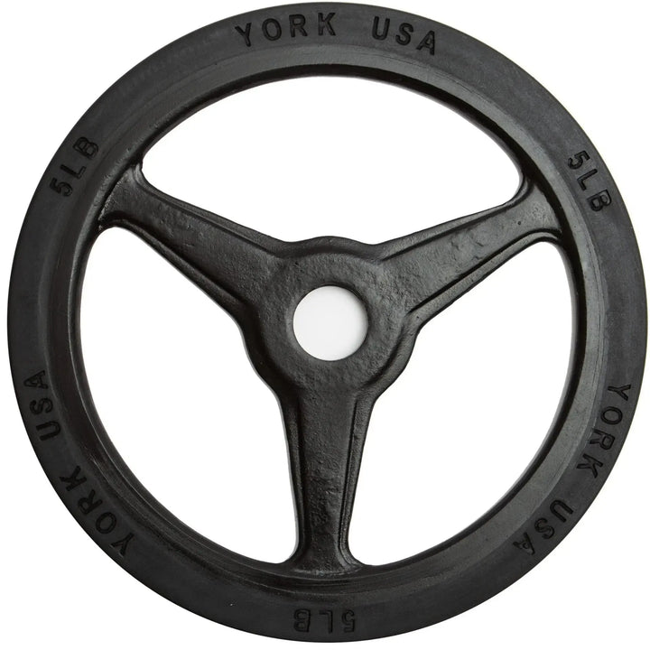 A York Barbell Bumper Grip Plate features a black, three-spoked design with York USA and 5 LB around the edge. Its rimmed with rubber for durability and has a central hole for barbell loading, ideal for commercial collections.