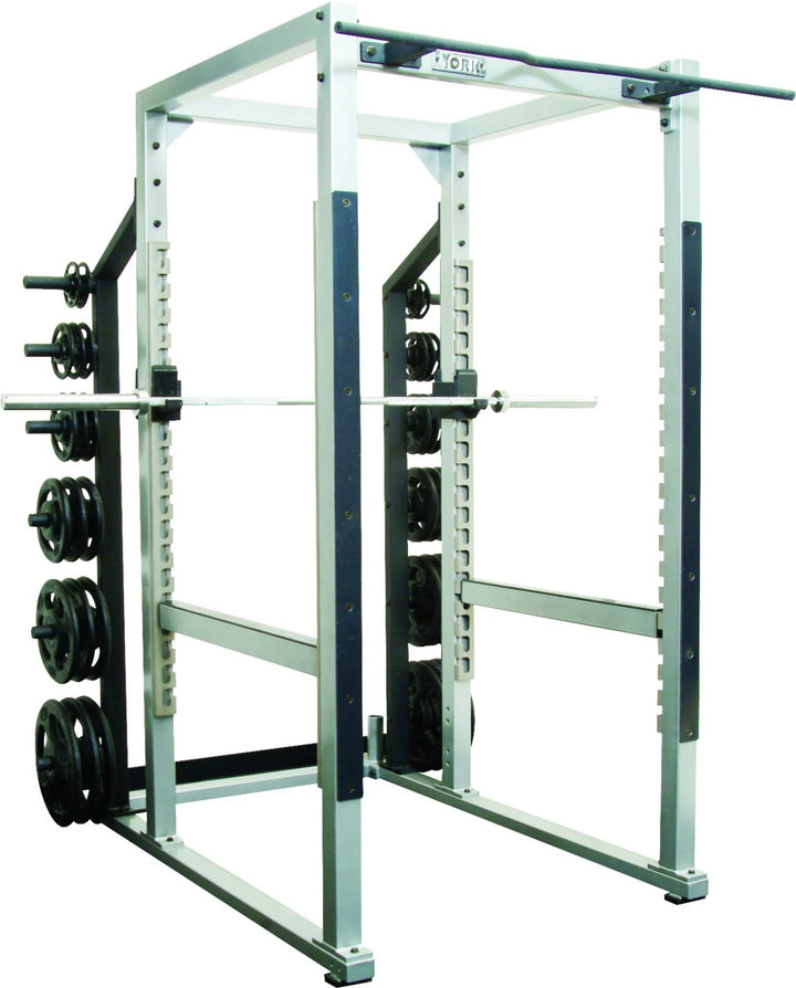 The York STS Power Rack w/ Hook Plates by York Barbell, in silver and black, features a barbell set on adjustable hooks and weight plates stored on pegs. Its perfect for strength training exercises like squats and bench presses with its sturdy metal construction suitable for commercial use.