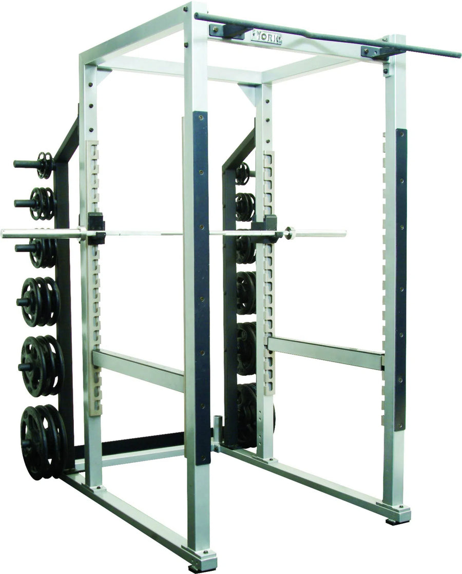 The York STS Power Rack w/ Hook Plates by York Barbell, in silver and black, features a barbell set on adjustable hooks and weight plates stored on pegs. Its perfect for strength training exercises like squats and bench presses with its sturdy metal construction suitable for commercial use.
