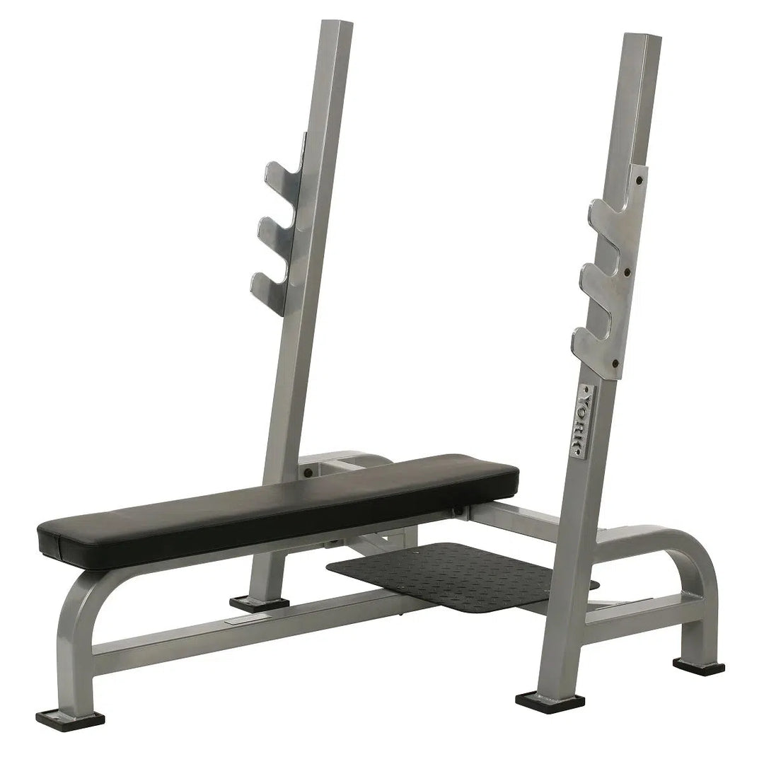 The York STS Olympic Flat Bench Press by York Barbell features heavy contour foam padding, a gray seat and backrest, chrome bar holders, an adjustable hook barbell rack with 3 holders, and a sturdy frame with supportive legs for stability.