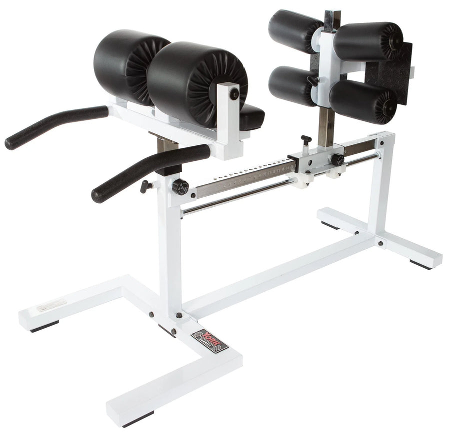 The York STS Glute Ham Developer Machine by York Barbell is a versatile, white hamstring trainer with black padding and adjustable settings. It features front handles, knee pads, and ankle supports for exercises targeting glutes and strengthening the lower back.
