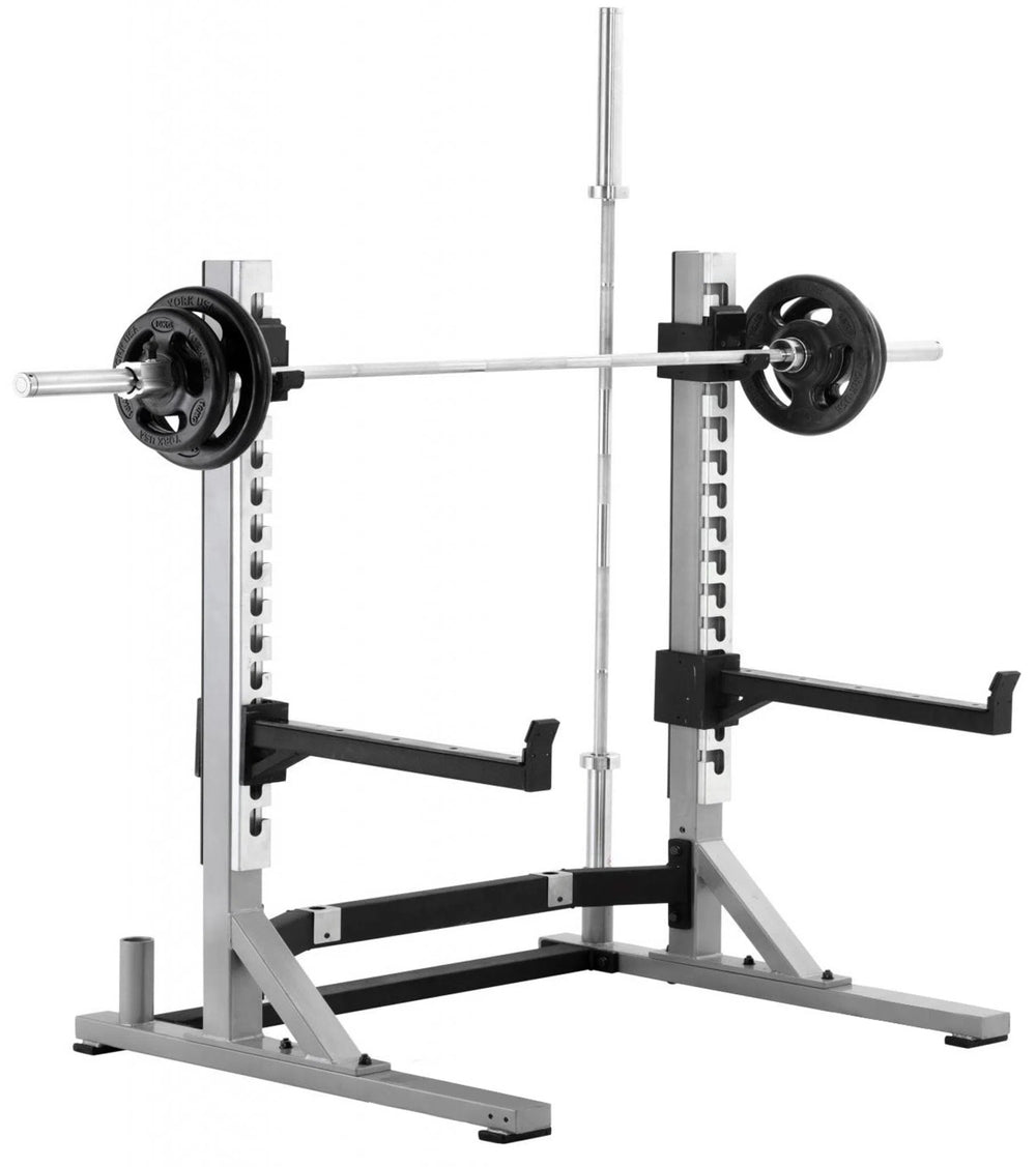 The York Barbell STS Collegiate Squat Rack is compact, with adjustable supports and safety catches. A barbell with weight plates sits at shoulder height, perfect for strength training enthusiasts ready for their next lift.