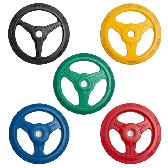 A York Bumper Grip Plate Set from York Barbell is arranged with five plates: black, yellow, red, green, and blue. Each plate features a central circular hole and three spokes extending to the rubber rim, creating a pattern when viewed from top left clockwise.