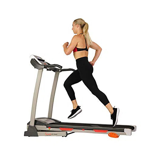 A blonde-haired person with a ponytail, in a black sports bra and leggings with sneakers, runs on the Sunny Health & Fitness Premium Folding Treadmill, featuring a compact control panel. It stands out elegantly against the pristine white background, providing an ideal fitness setup.