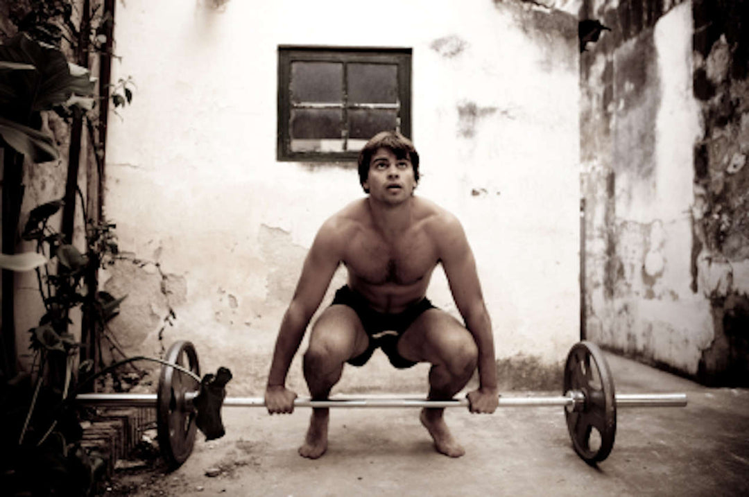 Lifter performing a rack pull from a power rack next to a lifter performing a deadlift from the floor
