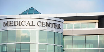 Modern building with large windows and a sign that reads Medical Center on the exterior, under a blue sky.