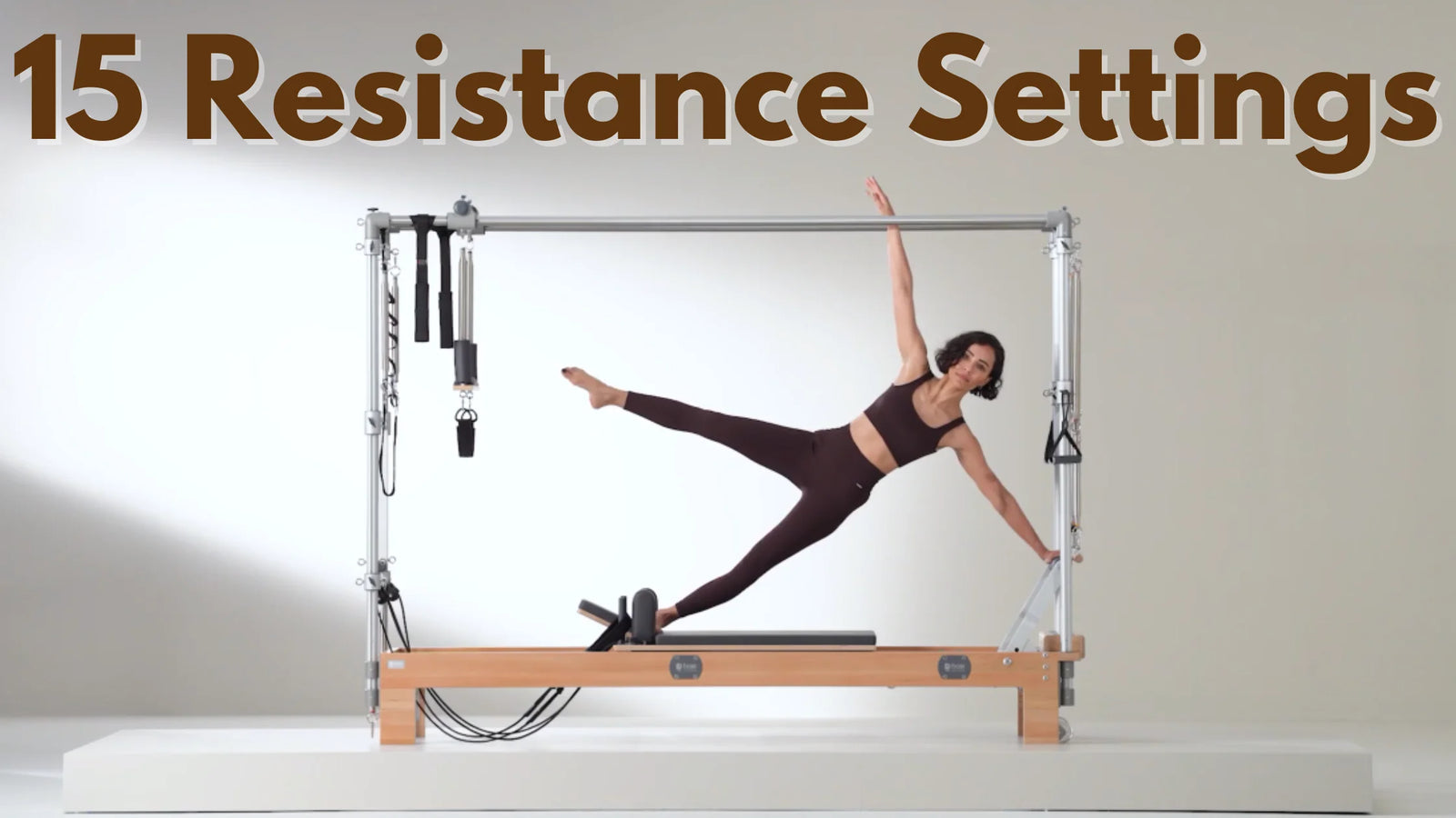 A woman in athletic wear demonstrates a side plank on a pilates reformer machine. The text above reads 15 Resistance Settings. The background is a neutral color, emphasizing the equipment and pose.