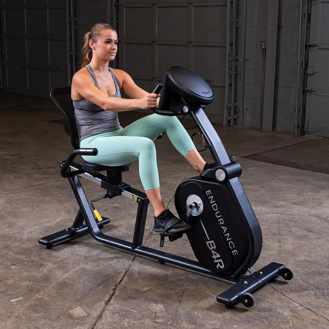 A woman training on the Body Solid Endurance Commercial Recumbent Bike B4RB