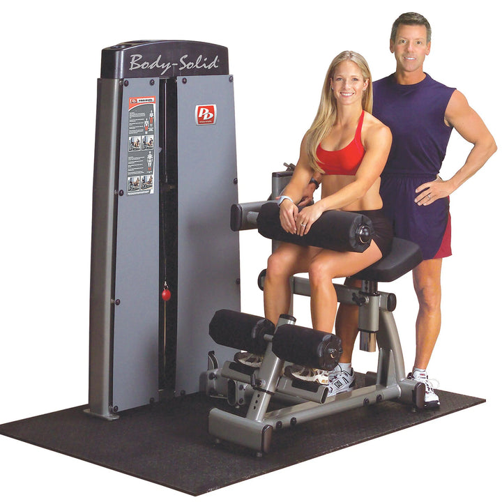 A woman training on the Body-Solid Ab Crunch & Back Extension Machine with her coach