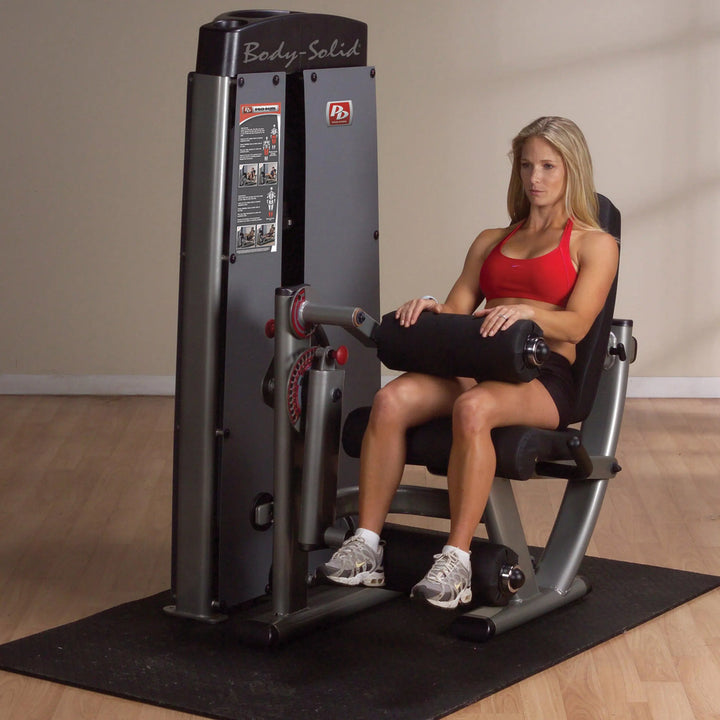 A woman training on the Body-Solid Leg Extension Leg Curl Combo Machine DLECSF