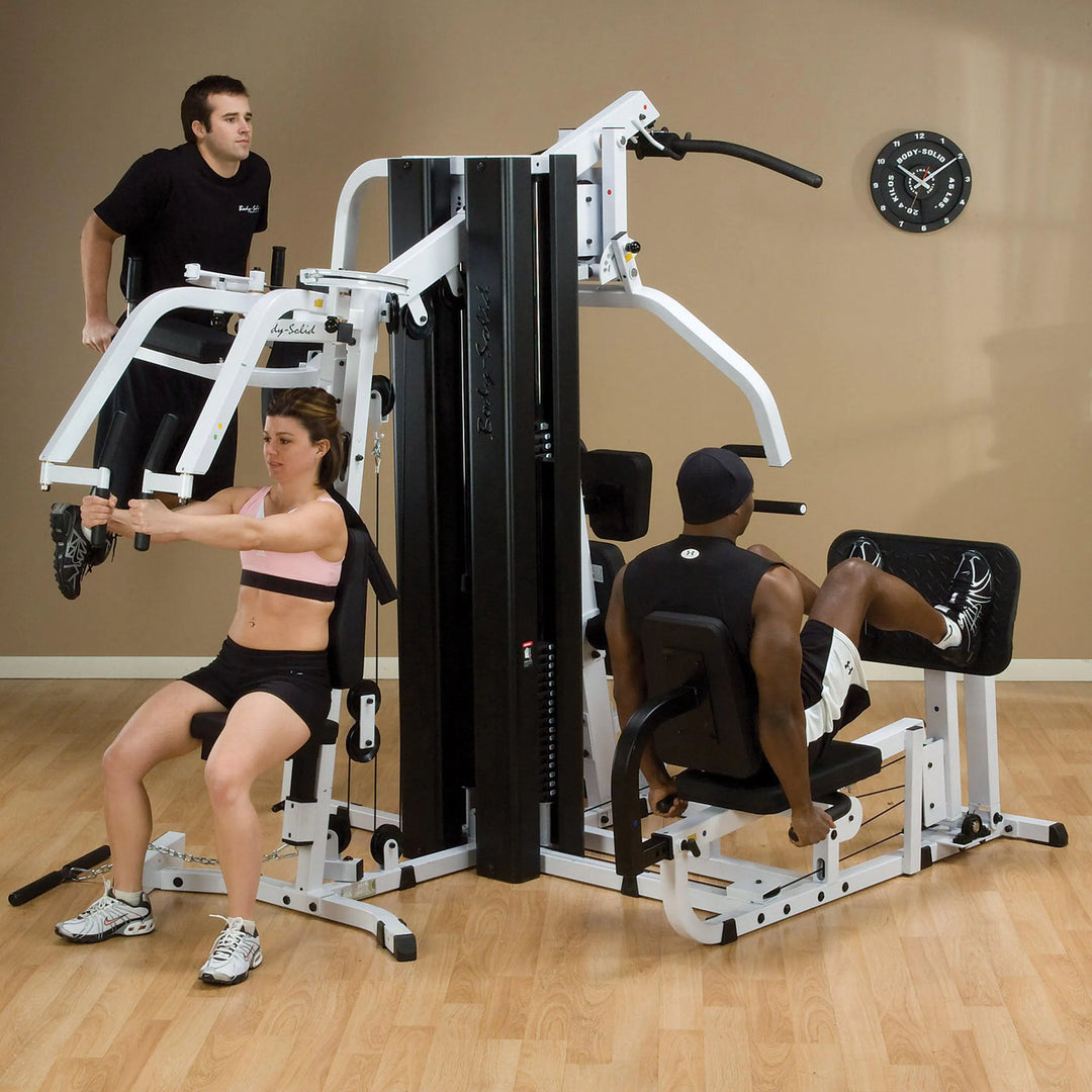 A group of 3 people training together on the Body-Solid Universal Weight Machine with Leg Press EXM3000LPS