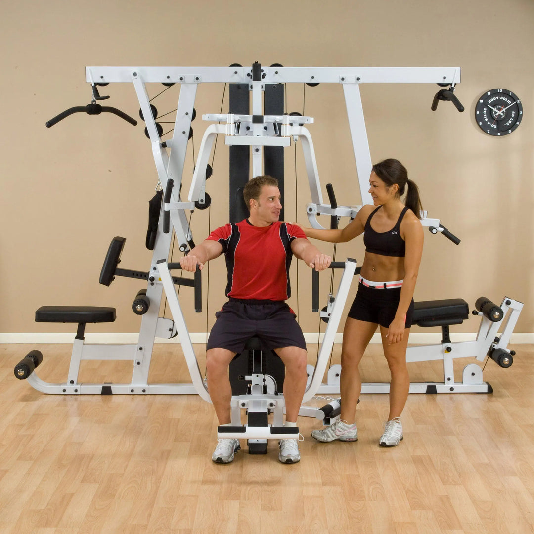 A woman training a man on the Body-Solid Universal Weight Machine with Leg Press EXM4000S