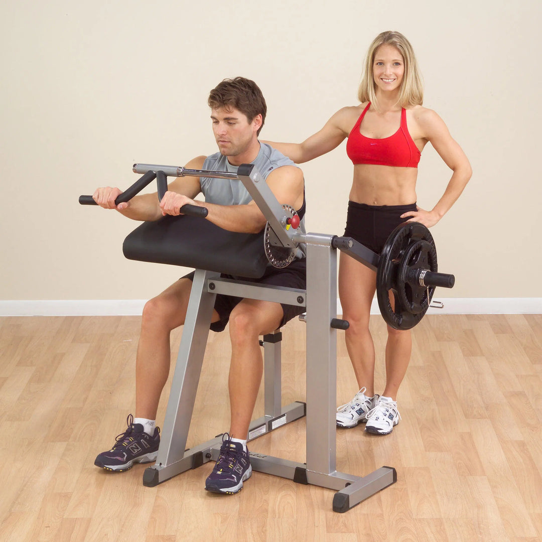 A man training with a woman on the Body-Solid Bicep Tricep Extension Machine GCBT380