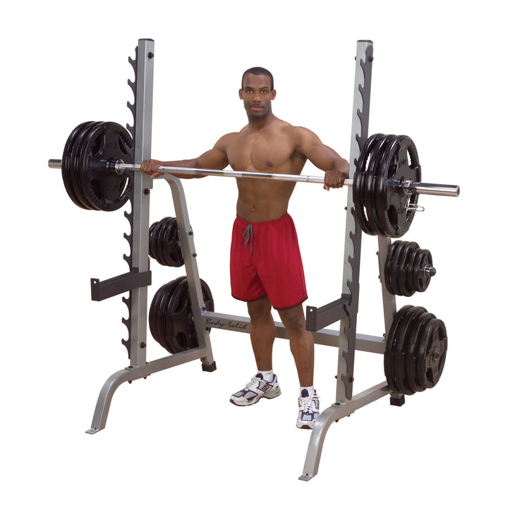 A man showcasing the Body-Solid Squat and Bench Rack GPR370 with barbell and weight plates