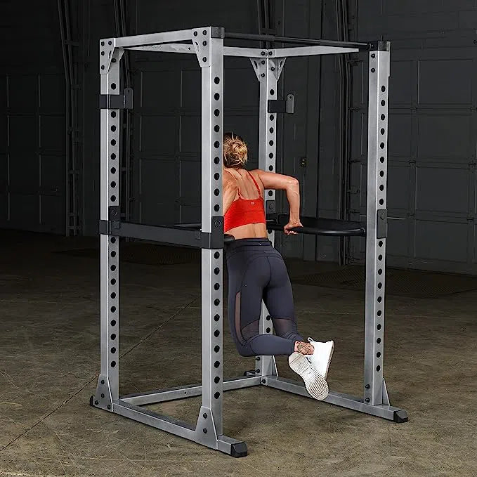 A woman showcasing an attachment for the Body-Solid Power Rack Set GPR378P4