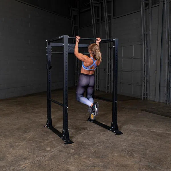 A woman doing chin ups on the Body-Solid Power Rack with Pulley System GPR400