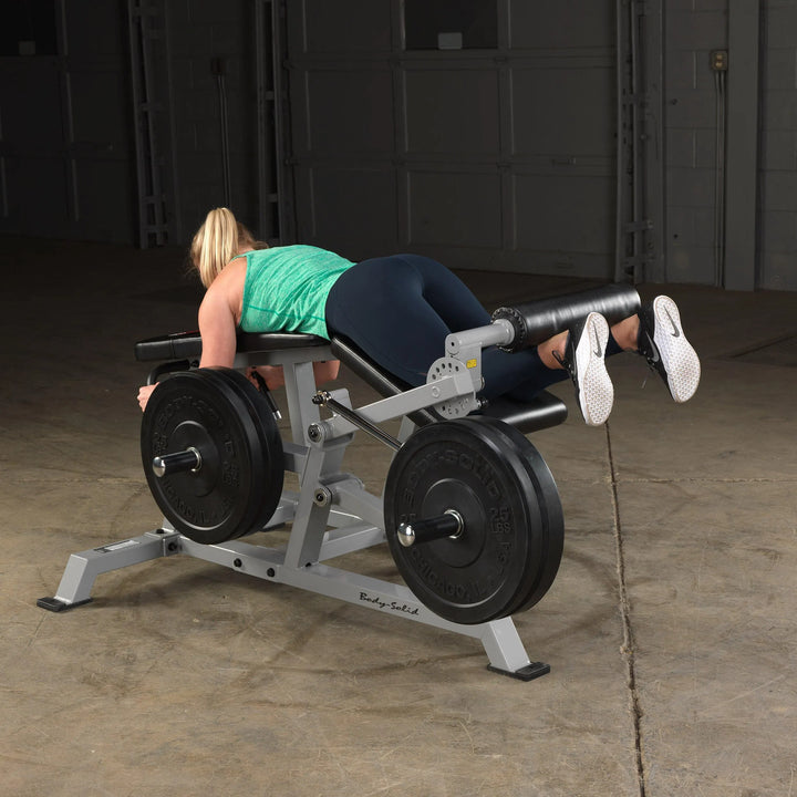 A woman training on the Body-Solid Leg Curl Machine LVLC