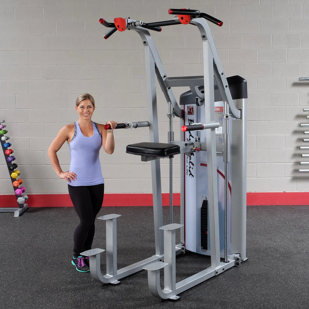 A woman showcasing the Body-Solid Assisted Pull Up Machine S2ACD