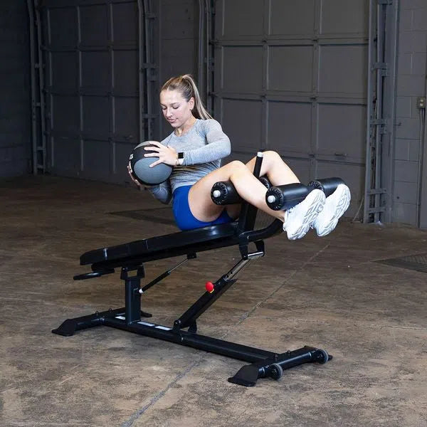 A woman doing medicine ball crunches on the Body-Solid Commercial Sit Up Bench SAB500