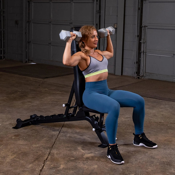 middle aged woman overhead dumbbell shoulder press workout on bench