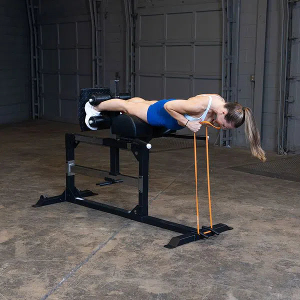 A woman training with resistance bands on Body-Solid Back Hyperextension SGH500