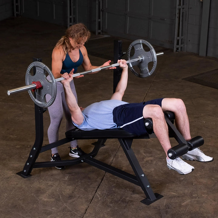 A woman spotting a man doing decline bench presses on the Body-Solid Commercial Olympic Decline Bench SODB250