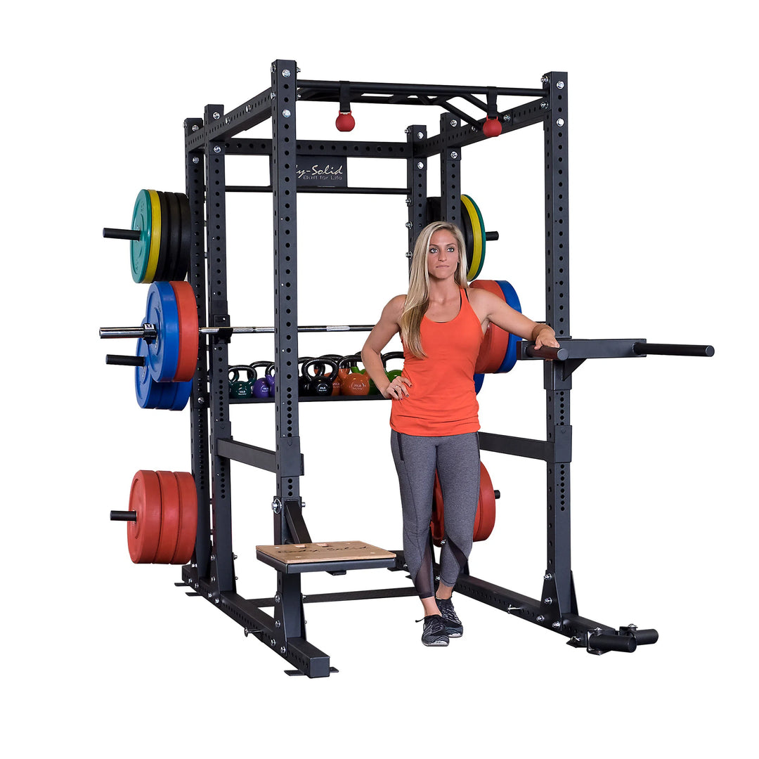 A woman showcasing attachments for the Body-Solid Commercial Power Rack Extended SPR1000Back