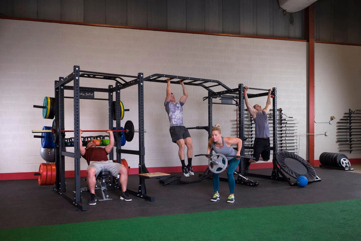 A group of four individuals training together on the Body-Solid Double Power Rack Extended SPR1000DB-Back