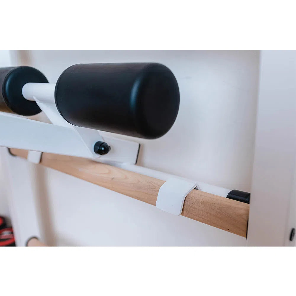 Close-up of the BenchK Pro Gym Swedish Ladder (723) featuring a wooden exercise bar on a white frame and padded black support roll, ideal for stretching or pulldowns.