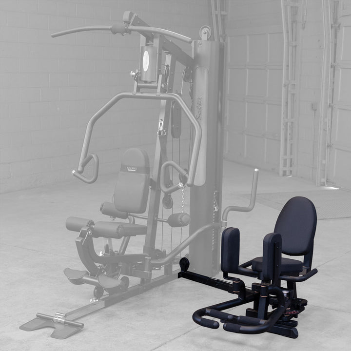 Angled view of the Body-Solid GIOT inner and outer thigh station fitted to a home gym