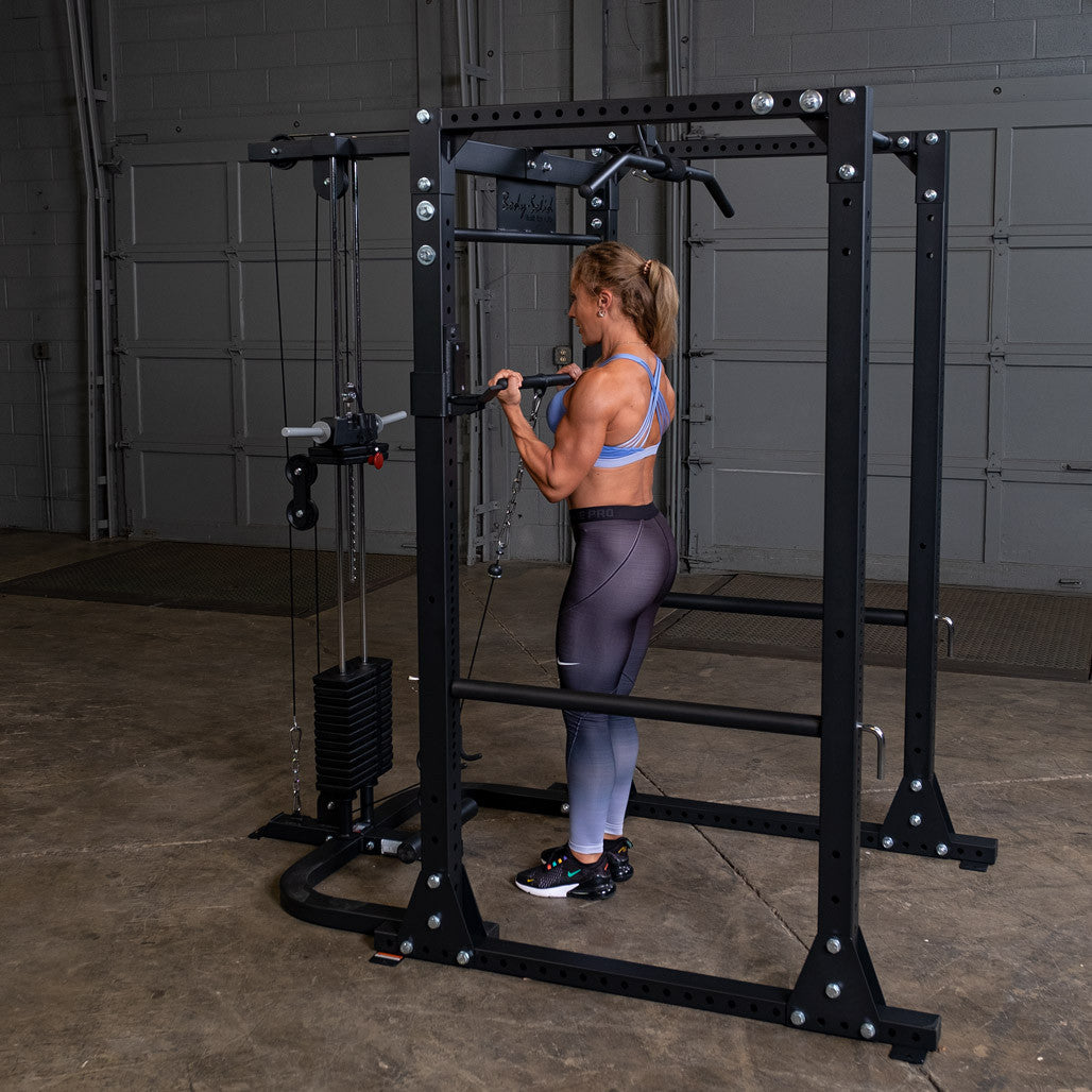 Woman doing a standing high pulley row on a Body-Solid GPR400 power rack fitted with the GLA400 lat attachment and a selectorized weight stack