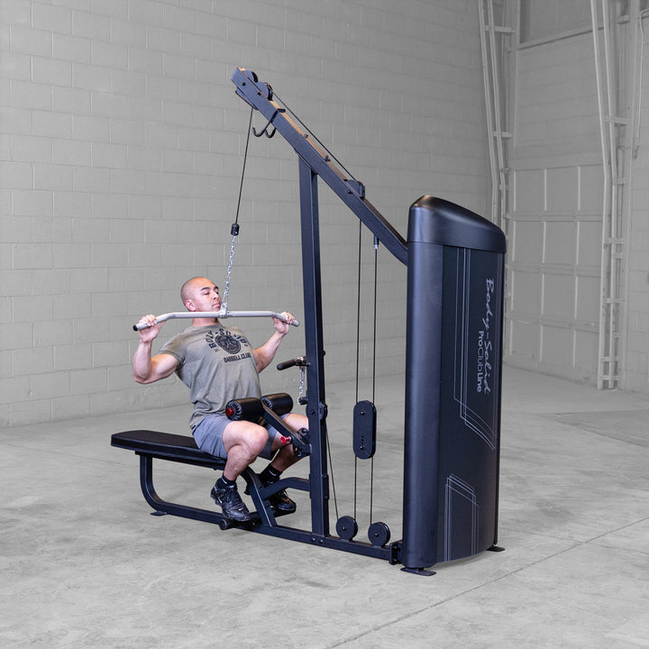 Body-Solid S2LATX lat pulldown and mid row machine photographed from the lat pulldown side, with the traditional lat bar hanging from the high pulley above the seat and thigh pad.