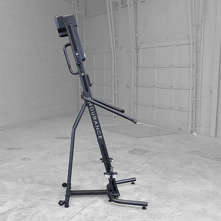 In a spacious, empty room with gray walls and large doors stands the sleek black Body-Solid Endurance Mountain Climber Machine (CL300). Designed for a full-body workout, it features adjustable resistance settings and displays Body-Solid Endurance on its side.