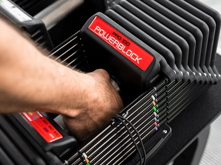 Close view of a hand on the 38 mm knurled stainless steel grip of the PowerBlock Commercial Pro 100
